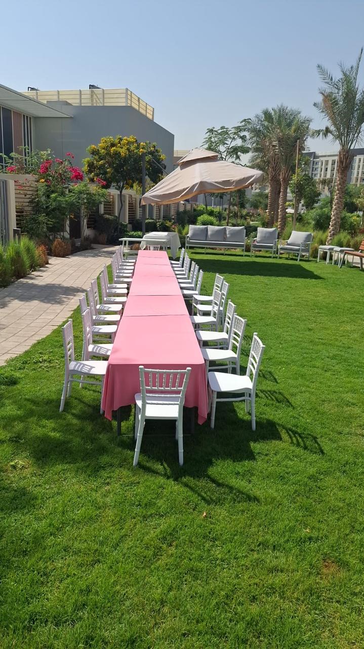 Garden table setup with pink linen and white chairs